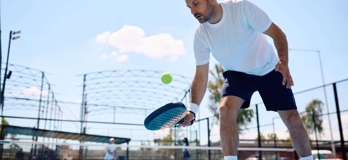 Paddle tennis player hitting the ball while playing match on the court.