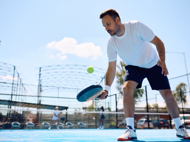 Paddle tennis player hitting the ball while playing match on the court.