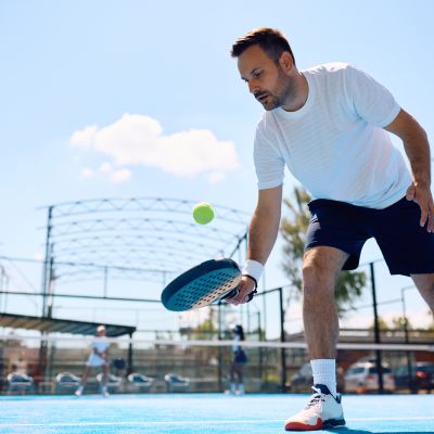 Paddle tennis player hitting the ball while playing match on the court.